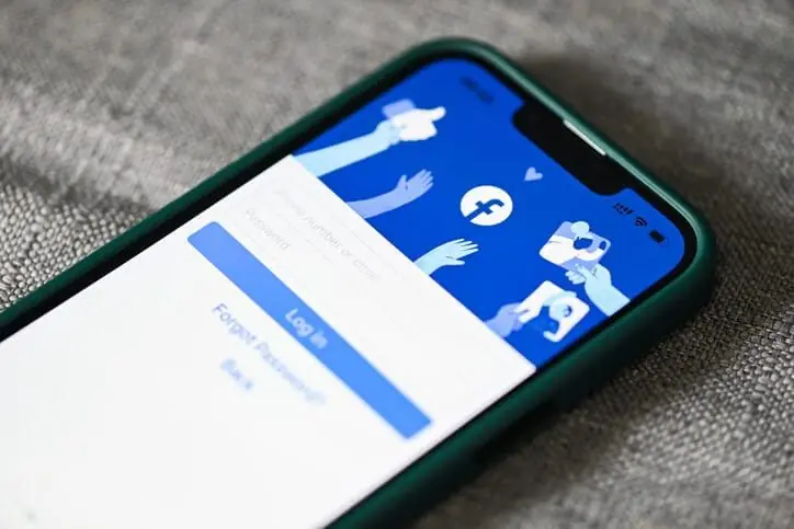 Celular sobre tecido exibindo a tela de login do Facebook