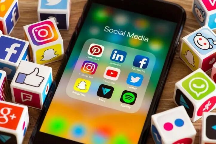 Celular com pasta Social Media cercado por cubos com logos de redes sociais como Instagram e Facebook