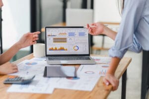 Dois analistas de dados ao redor de uma mesa trabalhando em um dashboard de marketing