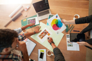 Equipe reunida em mesa de trabalho analisando materiais de identidade visual, cores e estratégias de branding.